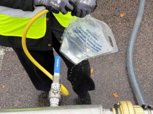 Bilden visar en hand som håller i en slag och fyller en ren mjuk plastpåse som är avsedd för dricksvatten