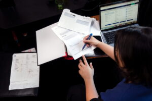 Person sitter vid ett skrivbord med en laptop och fakturor för att betala sin VA-faktura.